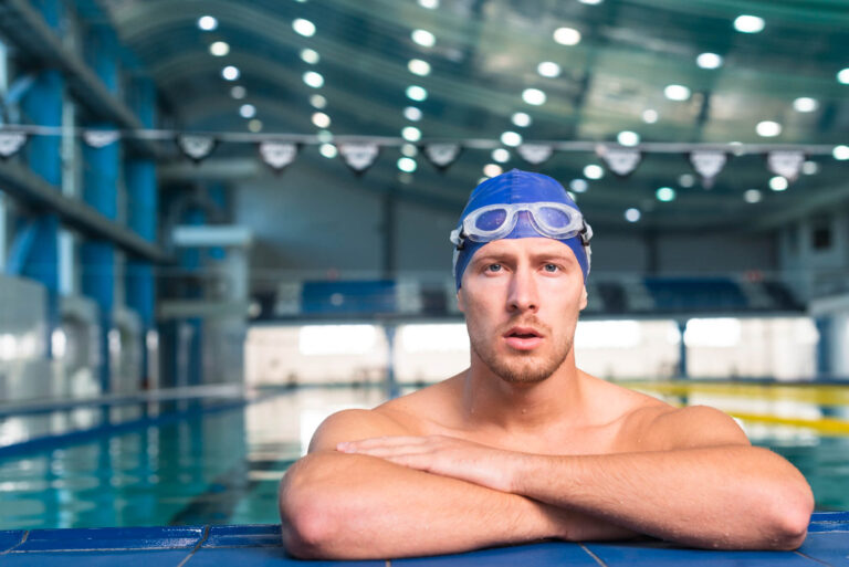 Guy sitting on the side of a Olympic swimming pool